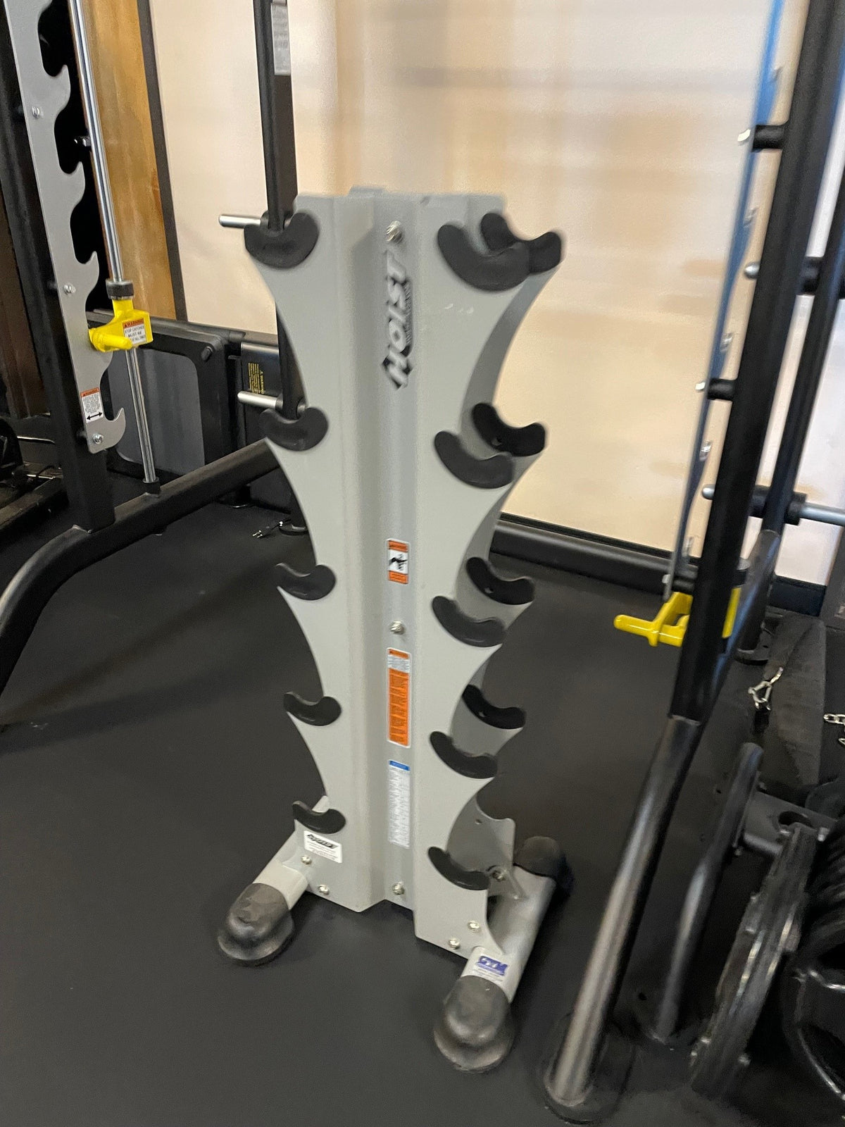 Used Hoist five-pair vertical dumbbell rack in white, empty, on a gym floor