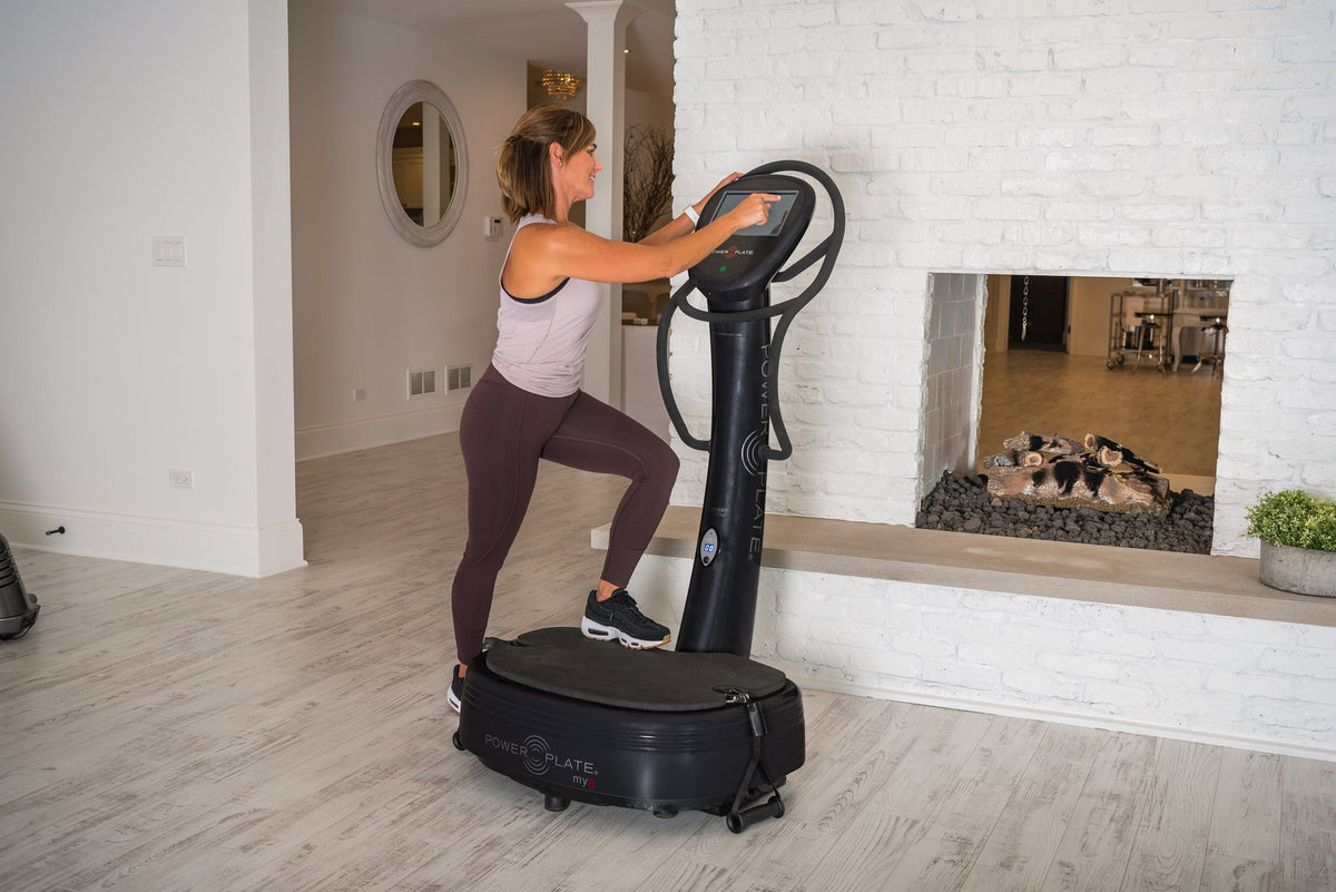 Woman doing a step-up holding the handles of a Power Plate my8
