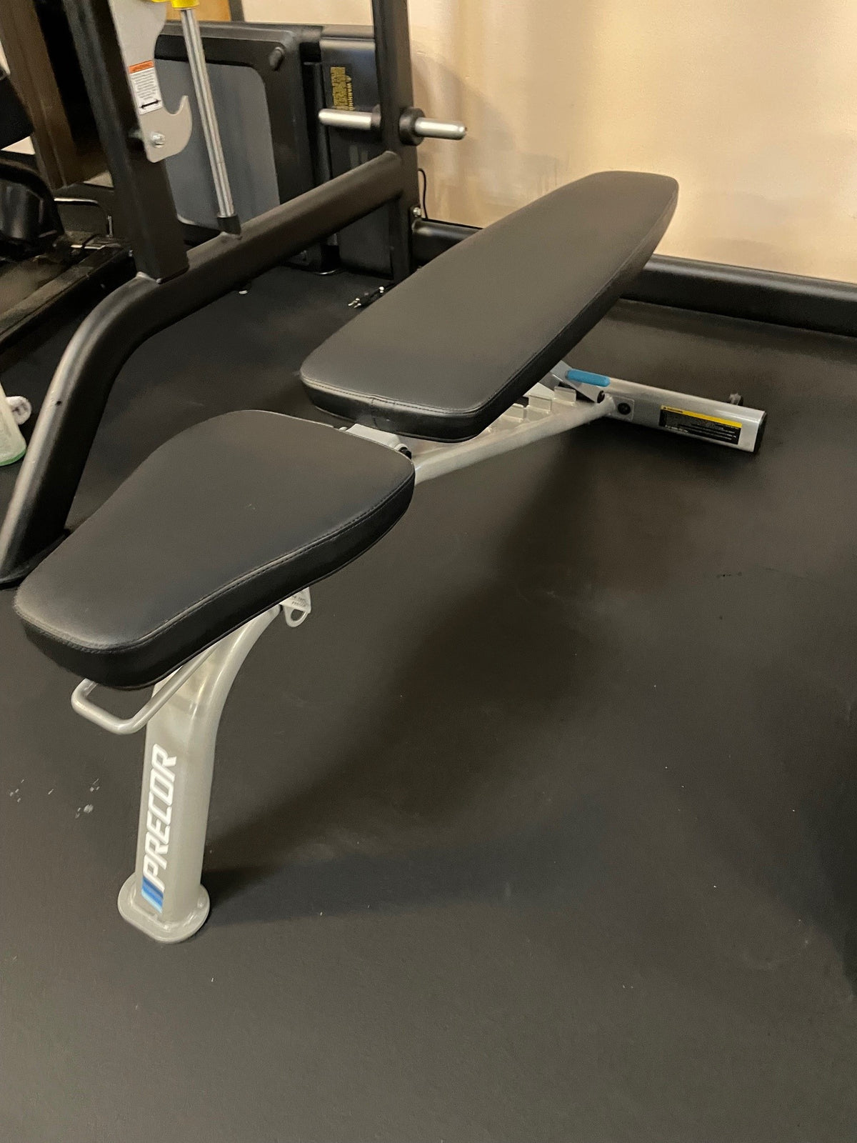 Used Precor adjustable home bench with black pads in flat position